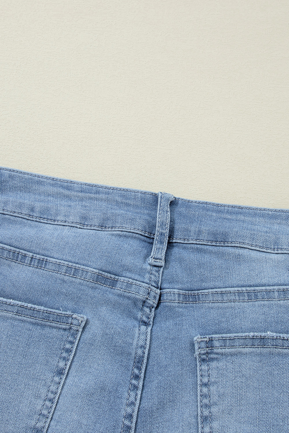 Schemerblauwe asymmetrische gescheurde jeans met knoopsluiting en hoge taille