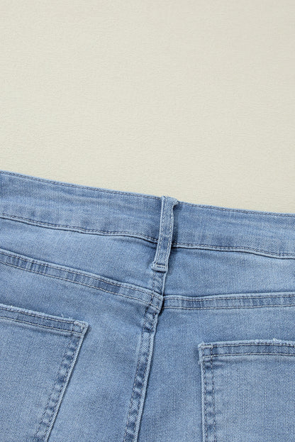 Schemerblauwe asymmetrische gescheurde jeans met knoopsluiting en hoge taille