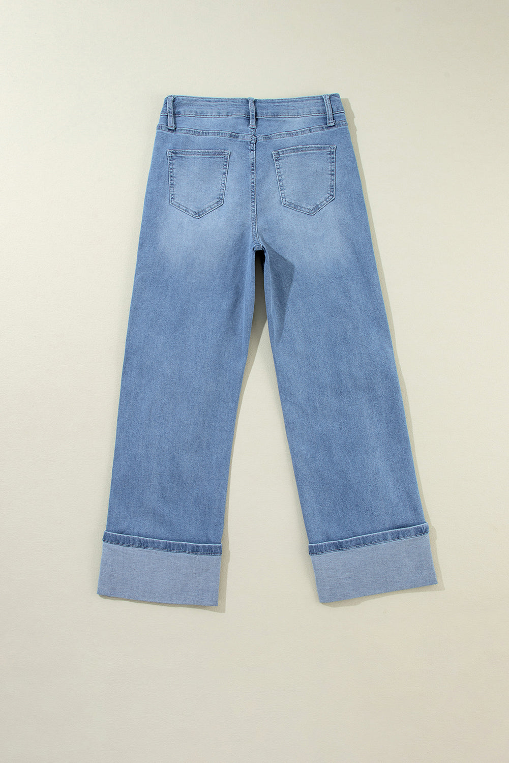 Schemerblauwe asymmetrische gescheurde jeans met knoopsluiting en hoge taille