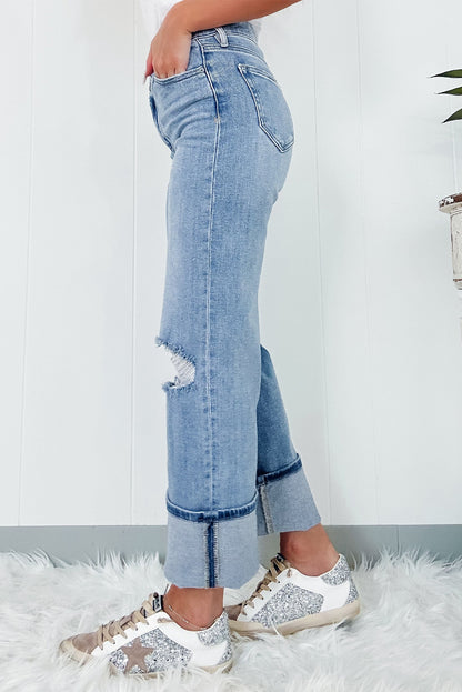 Schemerblauwe asymmetrische gescheurde jeans met knoopsluiting en hoge taille