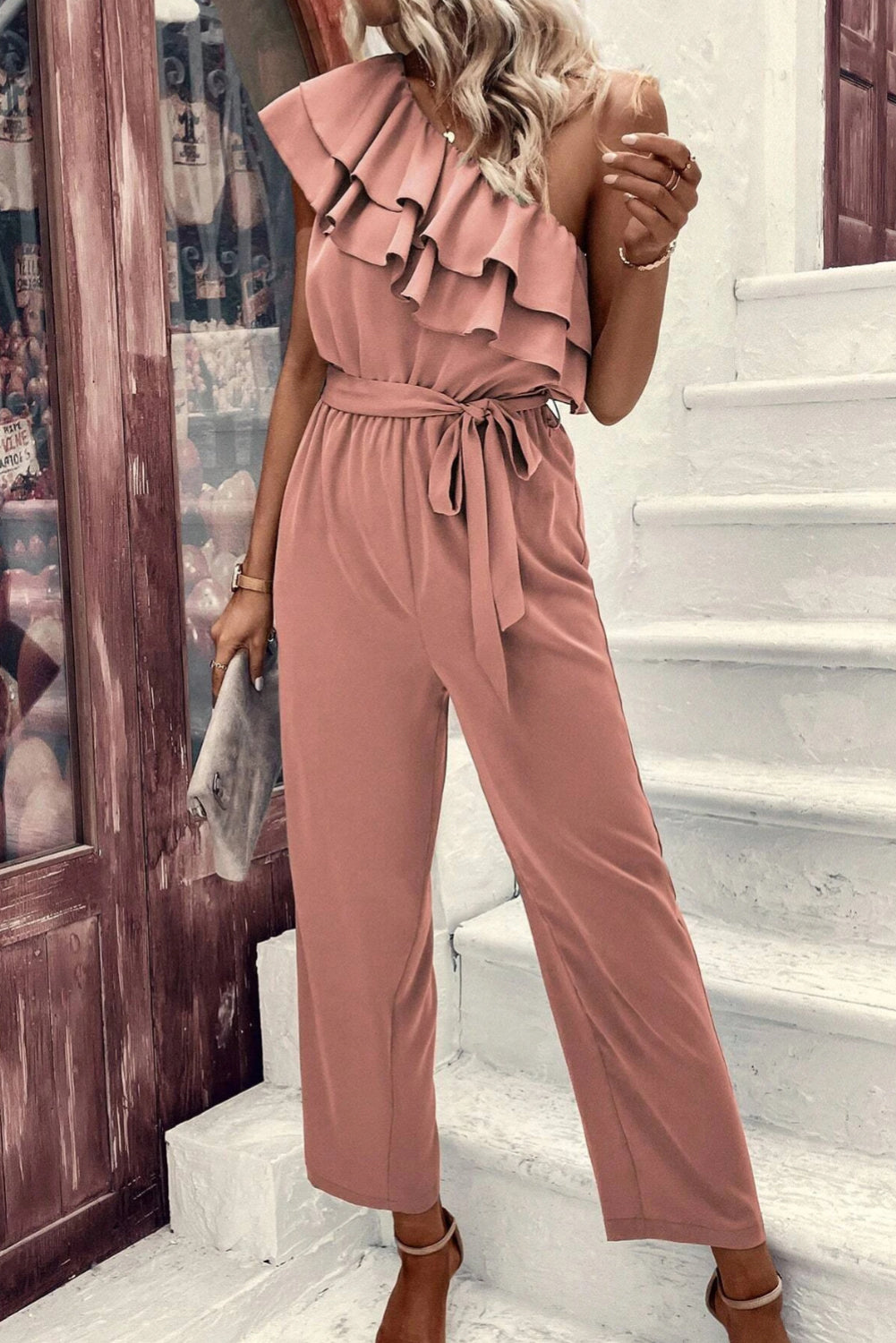 Stoffig roze jumpsuit met één schouder en ruches en riem