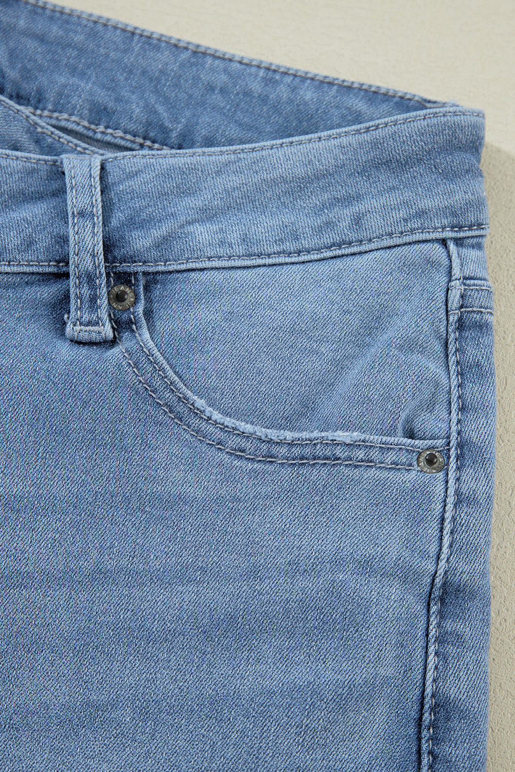 Schemerblauwe asymmetrische gescheurde jeans met knoopsluiting en hoge taille