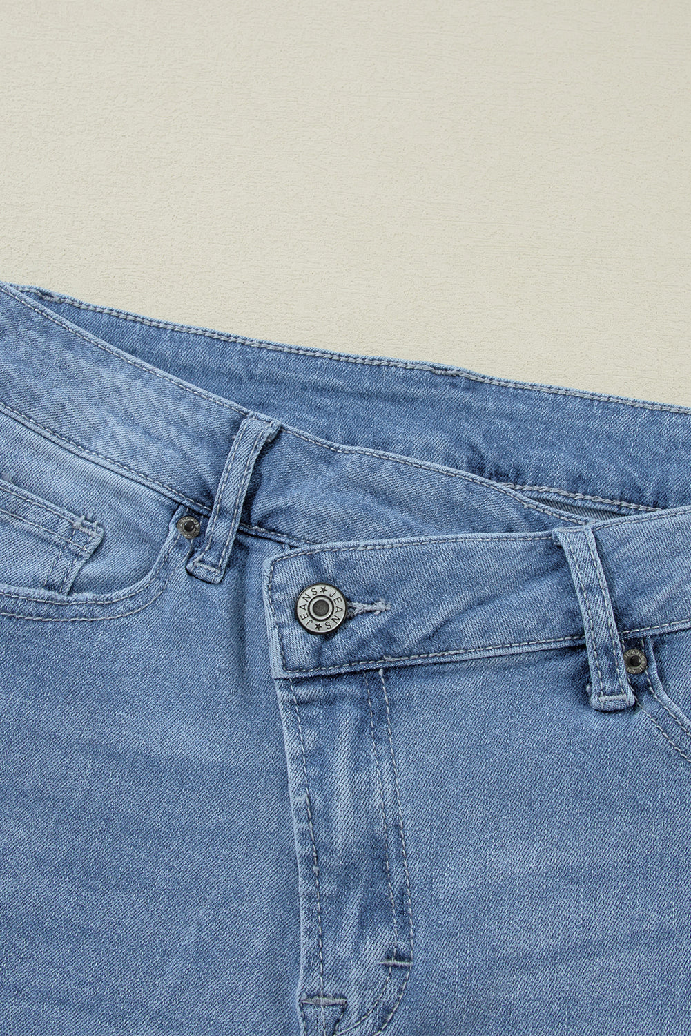 Schemerblauwe asymmetrische gescheurde jeans met knoopsluiting en hoge taille