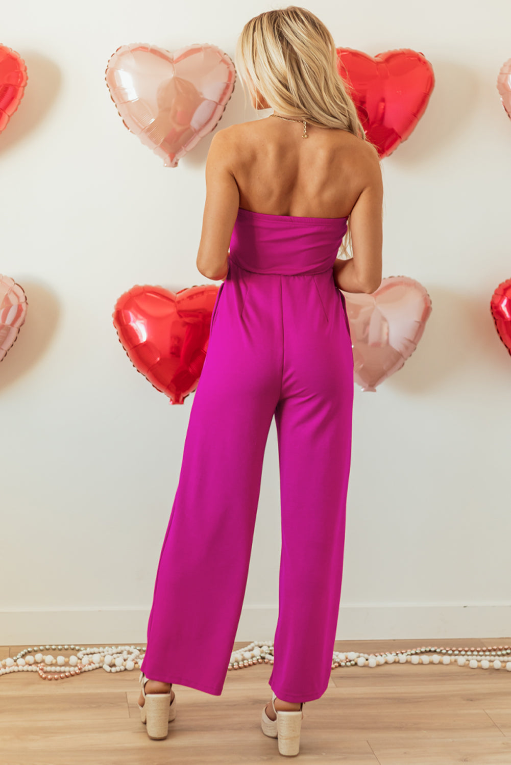 Felroze strapless jumpsuit met strik en wijde pijpen